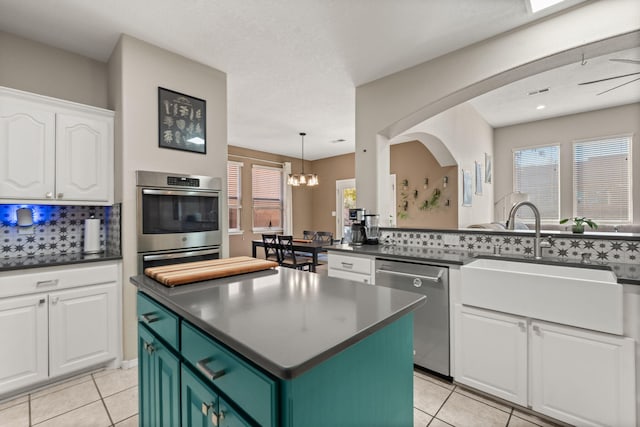 kitchen with sink, decorative light fixtures, a center island, appliances with stainless steel finishes, and white cabinets