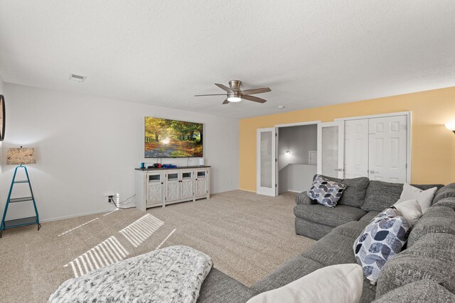 carpeted living room featuring ceiling fan and a textured ceiling