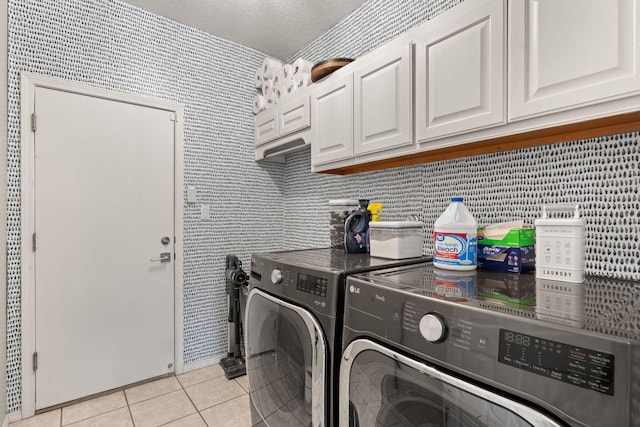 laundry area featuring cabinets, light tile patterned floors, and washing machine and clothes dryer