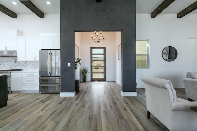 foyer featuring light hardwood / wood-style flooring, a towering ceiling, and beamed ceiling