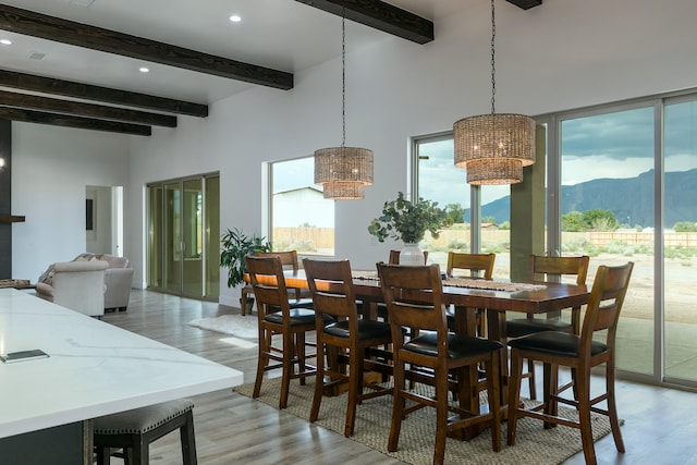 dining space with a notable chandelier, a mountain view, beam ceiling, and a wealth of natural light