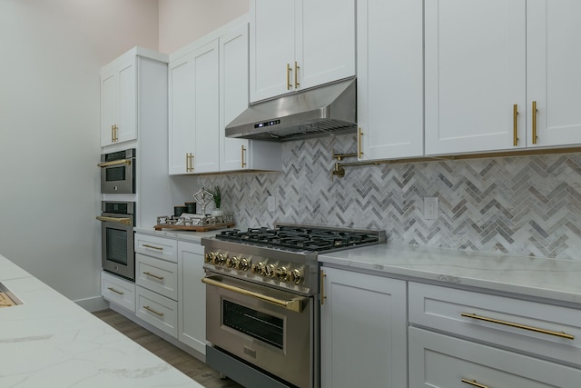 kitchen featuring light stone countertops, tasteful backsplash, white cabinetry, and high end stainless steel range