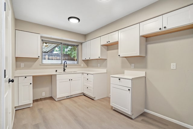 kitchen featuring white cabinets, light hardwood / wood-style flooring, and sink