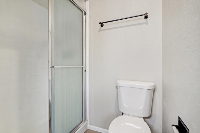 bathroom featuring walk in shower and toilet