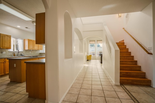 interior space with sink, a kitchen island, light tile patterned floors, and plenty of natural light