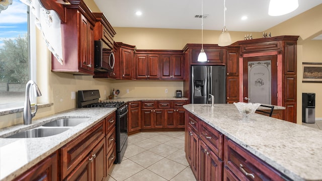 kitchen featuring stainless steel appliances, hanging light fixtures, sink, and light stone counters