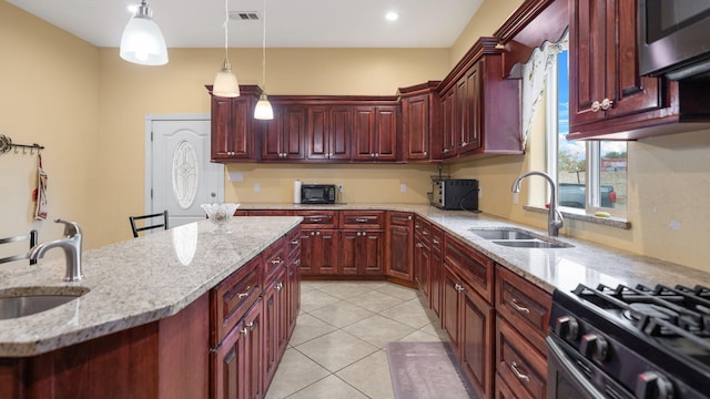 kitchen with a kitchen breakfast bar, sink, pendant lighting, and light stone counters