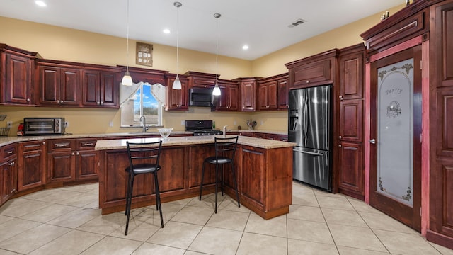 kitchen with stainless steel appliances, light stone countertops, a kitchen bar, hanging light fixtures, and a kitchen island