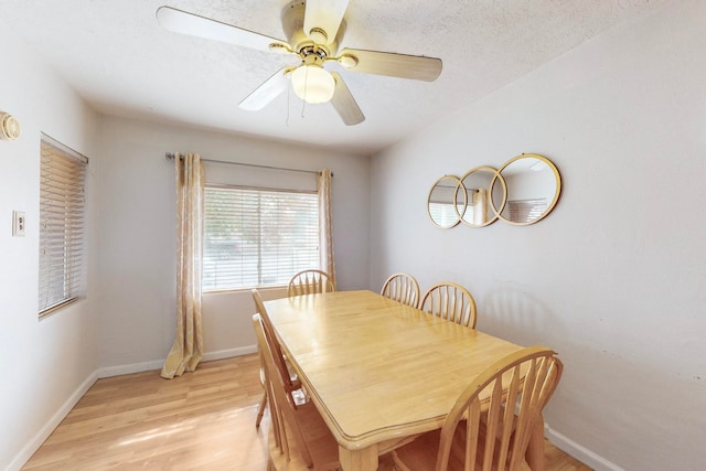 dining area with a textured ceiling, ceiling fan, and light hardwood / wood-style flooring