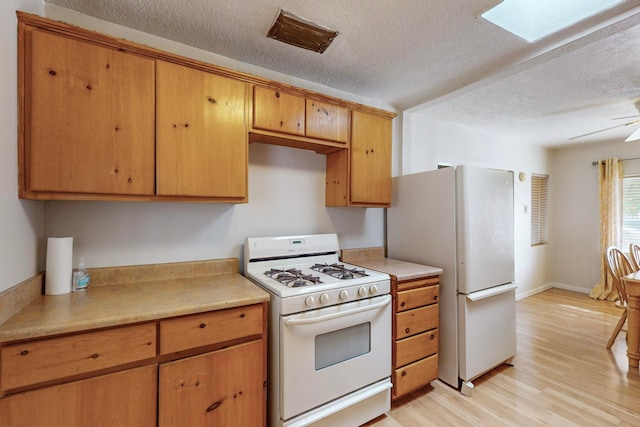 kitchen with light hardwood / wood-style floors, ceiling fan, a textured ceiling, a skylight, and white appliances