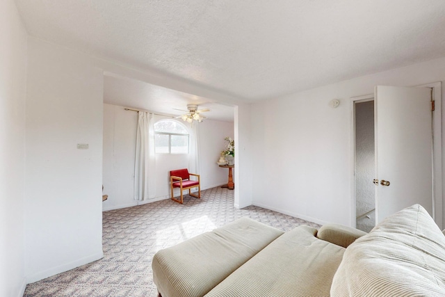 living room featuring a textured ceiling, light colored carpet, and ceiling fan