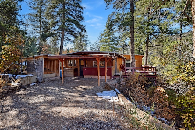 back of house featuring a wooden deck and a jacuzzi