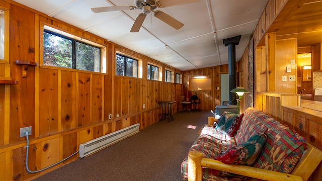 sunroom / solarium with baseboard heating, a wood stove, and ceiling fan