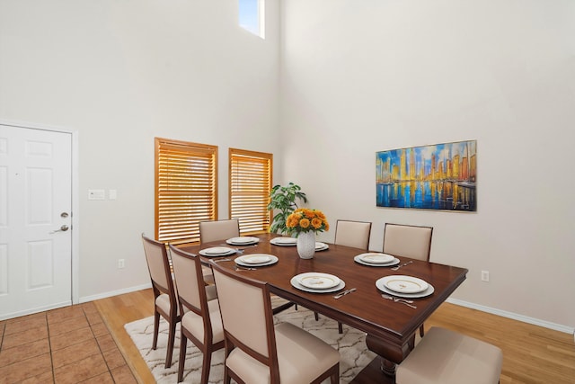 dining area with light hardwood / wood-style flooring and a high ceiling