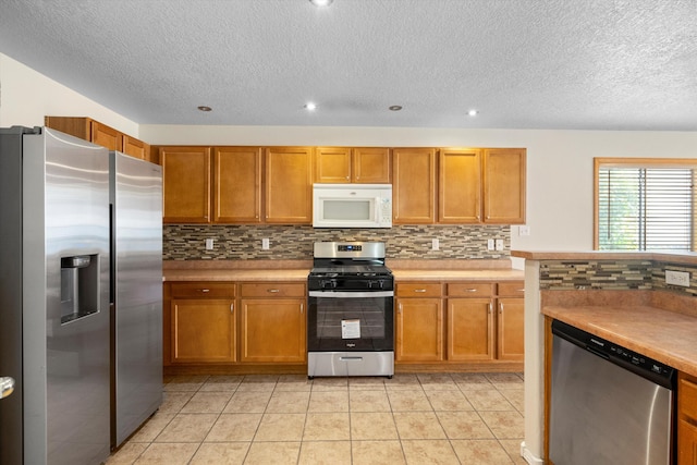 kitchen with light tile patterned floors, a textured ceiling, and appliances with stainless steel finishes