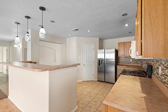 kitchen featuring stove, hanging light fixtures, stainless steel fridge, light tile patterned floors, and tasteful backsplash