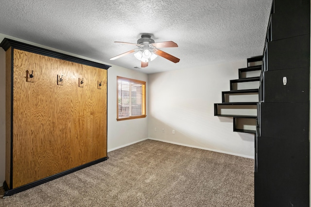 interior space with ceiling fan, dark carpet, and a textured ceiling