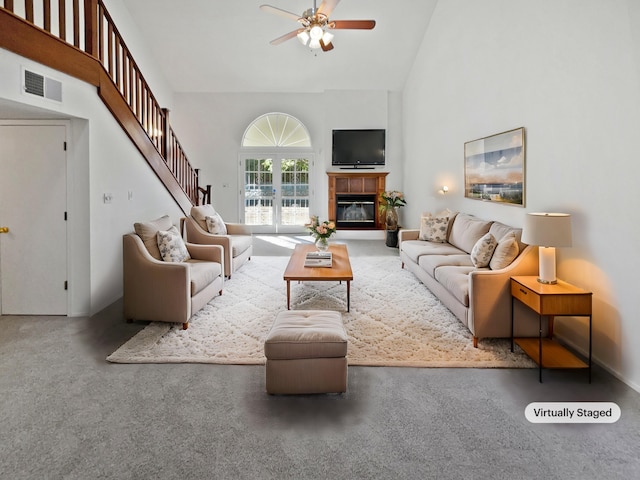 living room with a tile fireplace, carpet floors, high vaulted ceiling, and ceiling fan