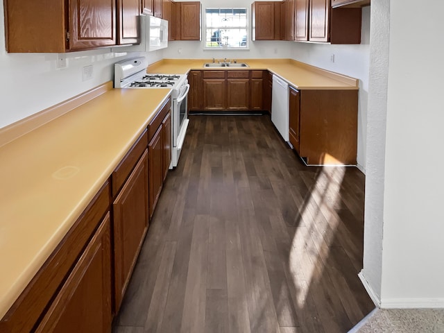 kitchen with sink, white appliances, and dark wood-type flooring