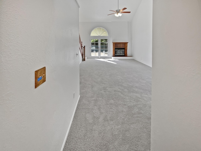 unfurnished living room with carpet floors, high vaulted ceiling, and ceiling fan