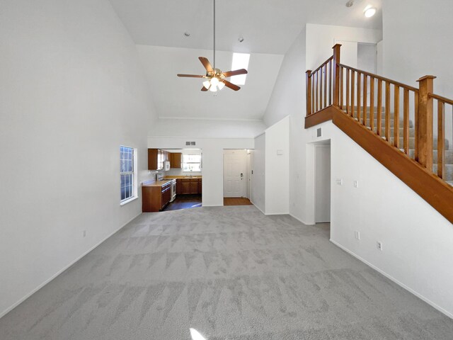 unfurnished living room with light colored carpet, high vaulted ceiling, and ceiling fan