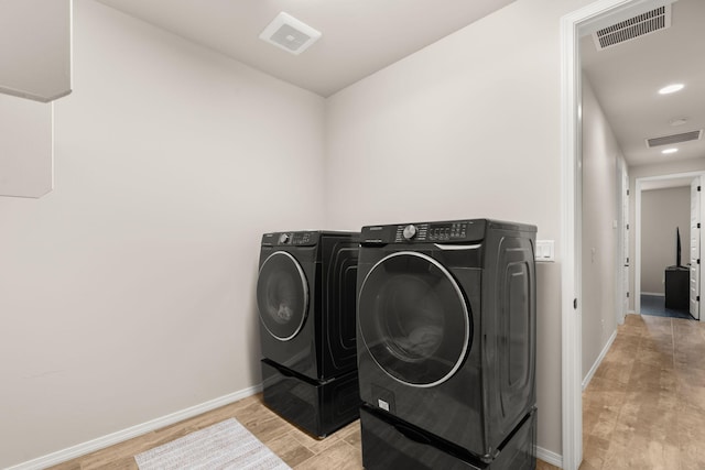 laundry room with independent washer and dryer and light hardwood / wood-style flooring