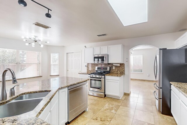 kitchen with light stone counters, sink, stainless steel appliances, and white cabinets