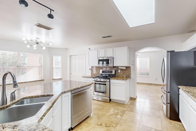 kitchen with white cabinetry, appliances with stainless steel finishes, sink, and light stone counters