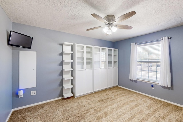 unfurnished bedroom with ceiling fan, light colored carpet, and a textured ceiling