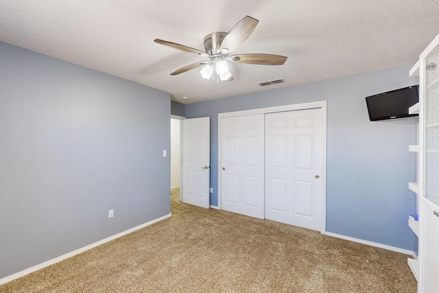 unfurnished bedroom with ceiling fan, carpet flooring, a textured ceiling, and a closet