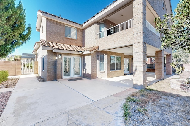 back of property featuring a patio, a balcony, and french doors