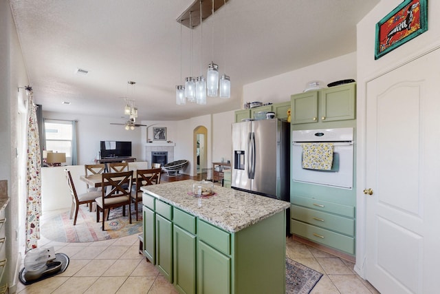 kitchen with a kitchen island, stainless steel fridge with ice dispenser, oven, hanging light fixtures, and green cabinetry