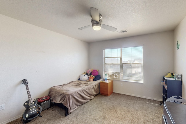 carpeted bedroom with ceiling fan and a textured ceiling