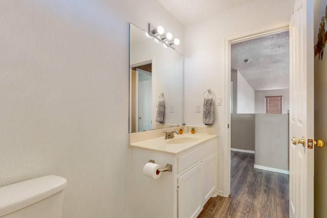 bathroom with vanity, wood-type flooring, a textured ceiling, and toilet