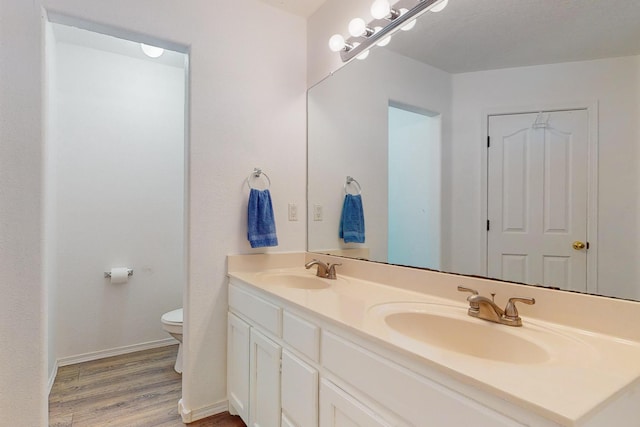 bathroom featuring wood-type flooring, vanity, and toilet