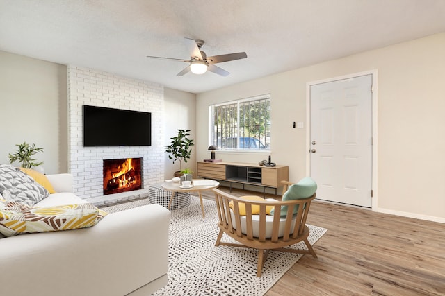 living room featuring ceiling fan, a fireplace, light hardwood / wood-style floors, and a textured ceiling