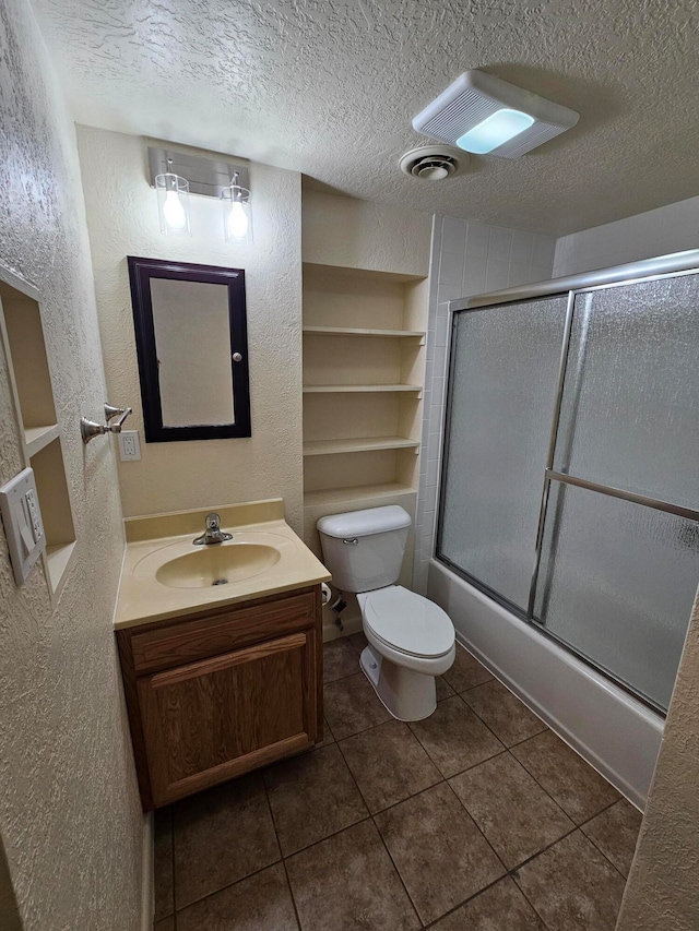 full bathroom featuring tile patterned flooring, a textured ceiling, toilet, and enclosed tub / shower combo