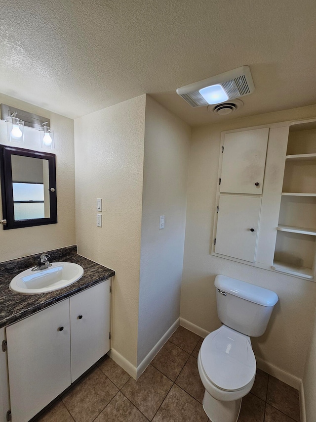 bathroom with toilet, vanity, a textured ceiling, and tile patterned floors