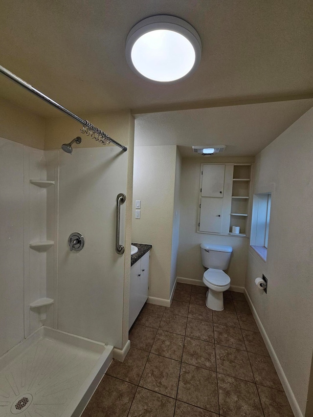 bathroom with tile patterned flooring, vanity, toilet, and walk in shower