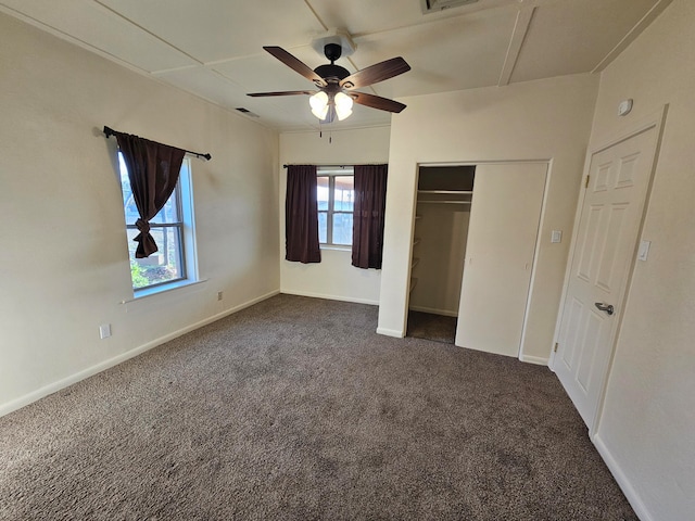 unfurnished bedroom with multiple windows, ceiling fan, a closet, and dark carpet