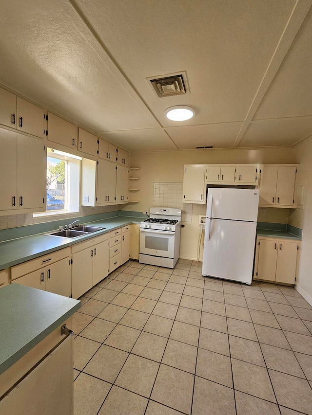 kitchen featuring a textured ceiling, white appliances, sink, and light tile patterned floors