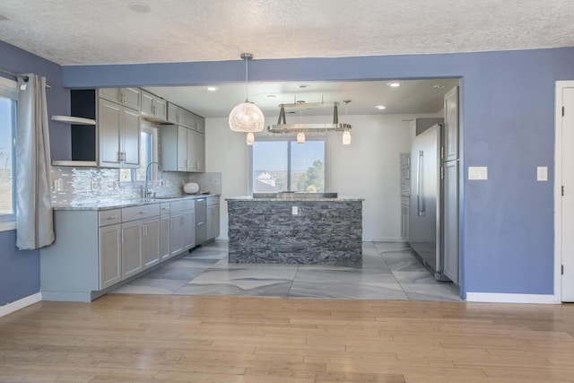 kitchen with gray cabinetry, tasteful backsplash, light wood finished floors, and pendant lighting