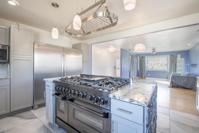 kitchen with gray cabinetry, open floor plan, hanging light fixtures, a center island, and high end appliances