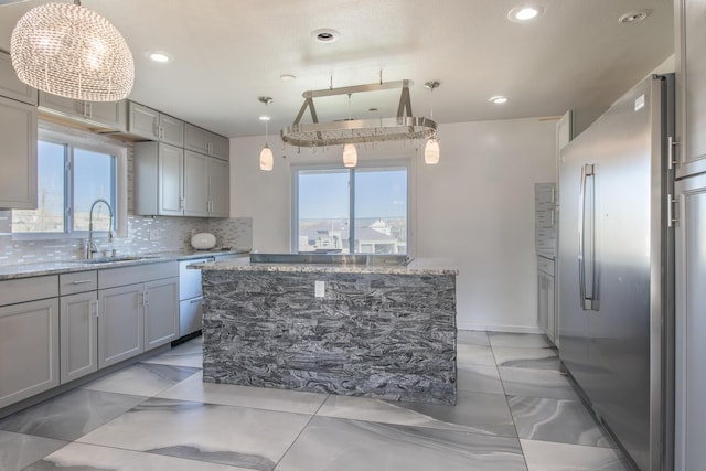 kitchen featuring gray cabinets, a kitchen island, freestanding refrigerator, and pendant lighting