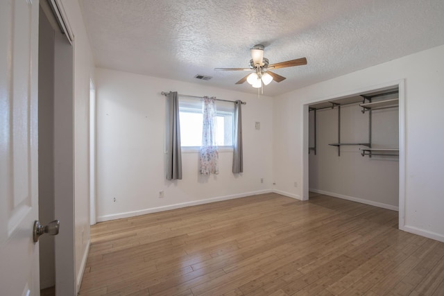 unfurnished bedroom featuring light wood-type flooring, baseboards, visible vents, and a textured ceiling