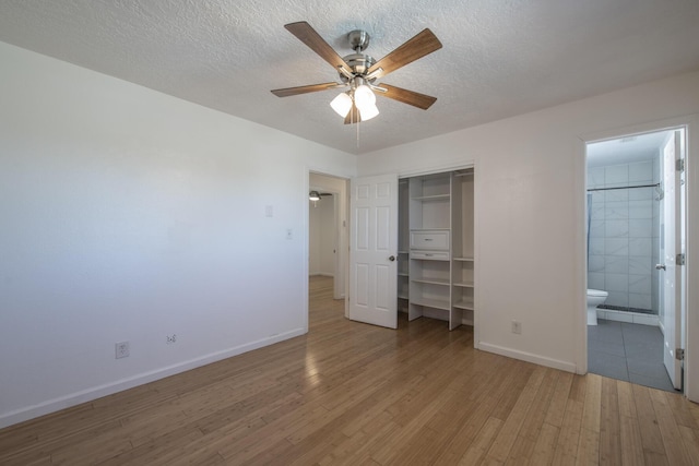 unfurnished bedroom with a textured ceiling, a closet, and light wood-style flooring