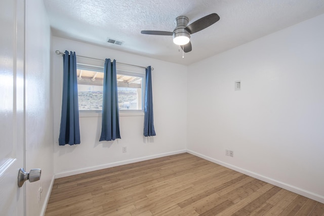 empty room featuring baseboards, visible vents, a ceiling fan, a textured ceiling, and light wood-style floors