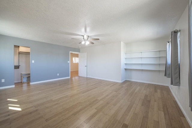 unfurnished living room featuring a textured ceiling, light wood finished floors, a ceiling fan, and baseboards