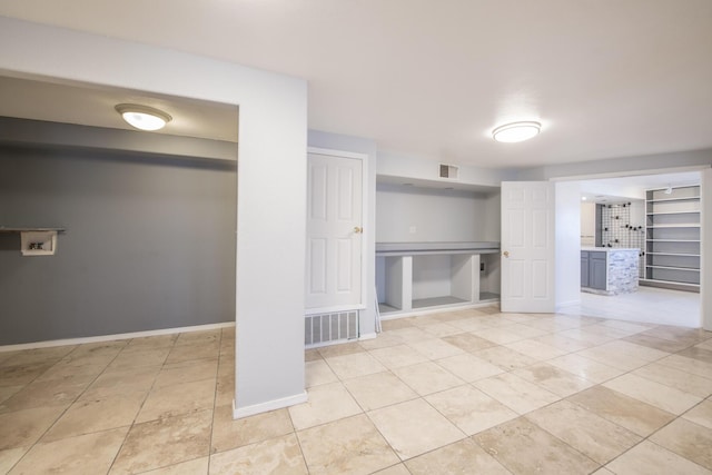 finished below grade area featuring light tile patterned floors, visible vents, and baseboards