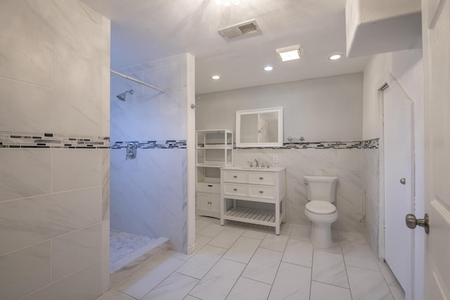 full bath with visible vents, toilet, walk in shower, vanity, and tile walls